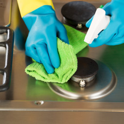 Gloved Hands Cleaning Stove Top Range with Spray bottle and Micr